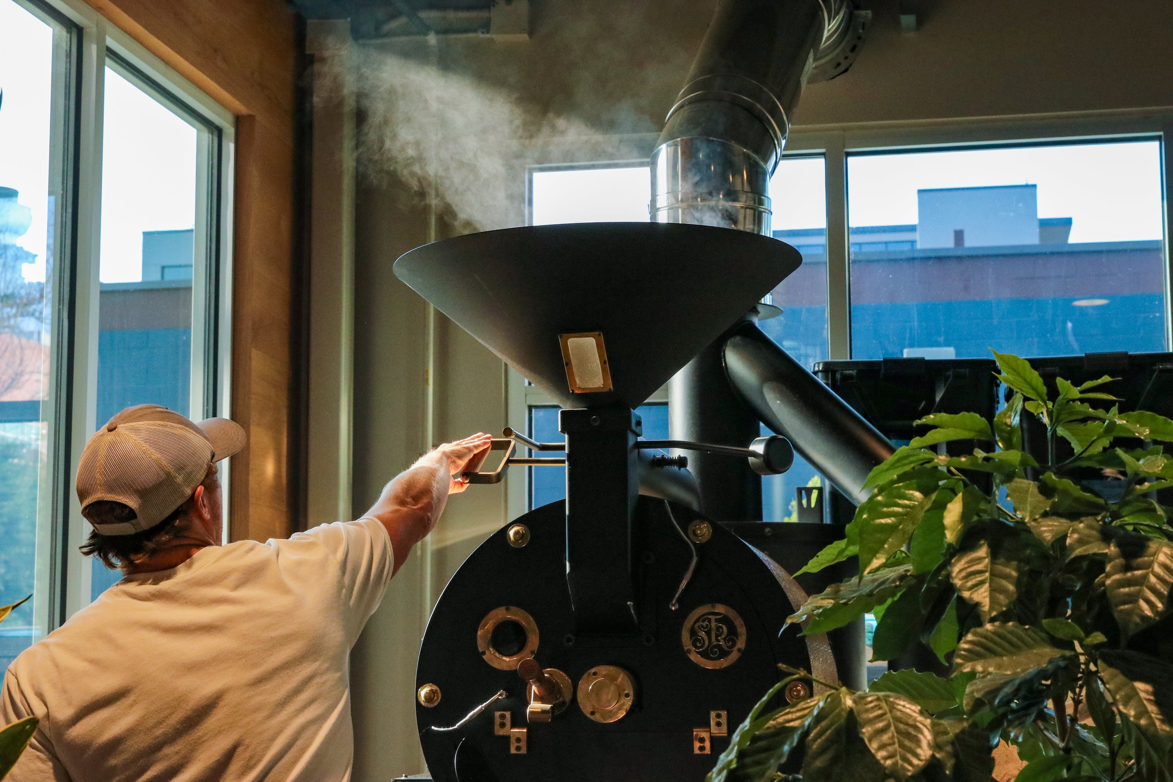 A coffee roaster operating equipment at a coffee shop, symbolizing Tannin's presence in local Charlotte cafes and markets where customers can find their post-coffee rinse. The image reflects Tannin’s connection to coffee culture and its commitment to supporting local businesses.