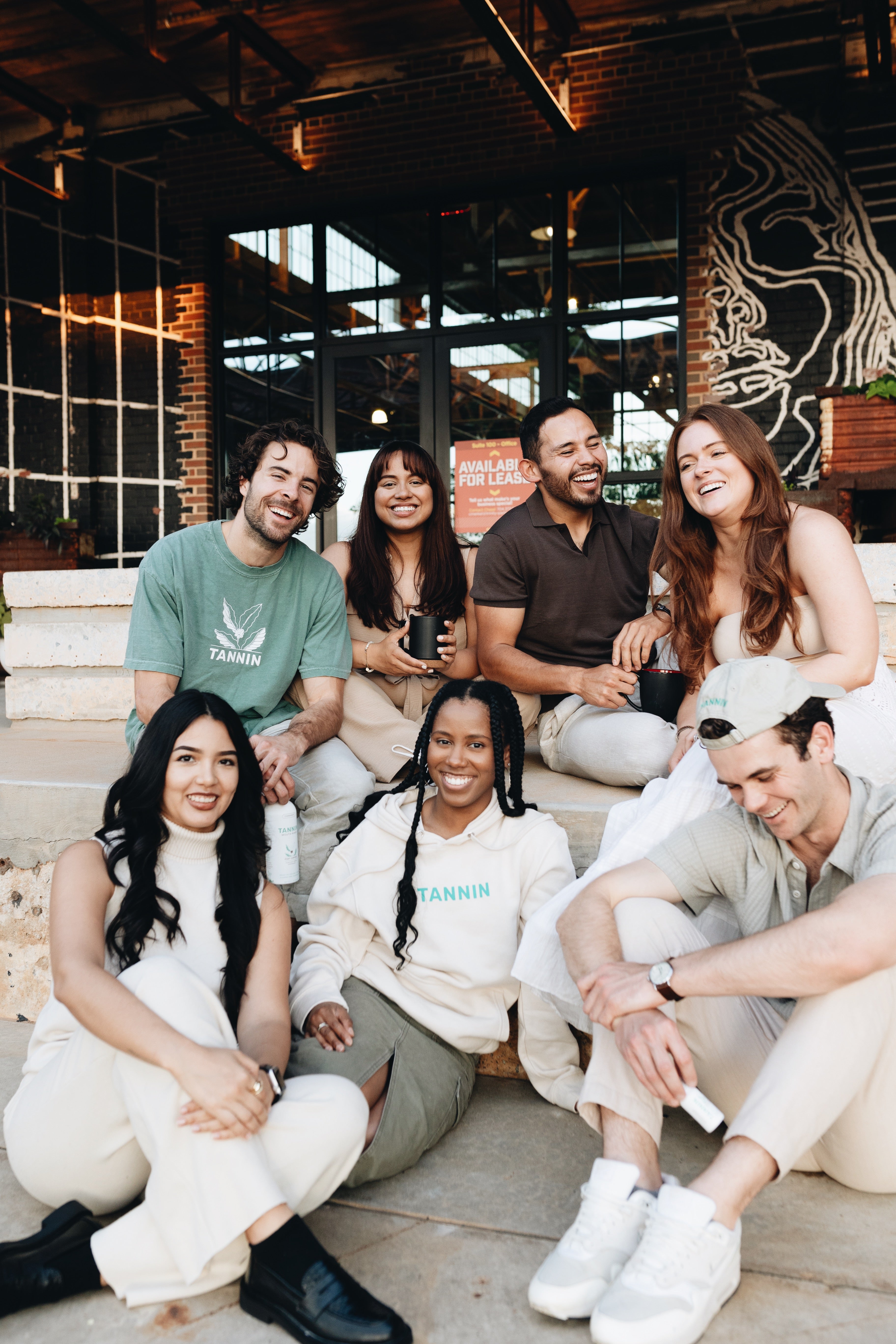 Members of Tannin's Brewville community gathered together, smiling and enjoying each other's company. A diverse group seated outdoors, wearing Tannin-branded apparel, reflects the brand's values of connection, confidence, and community. This group embodies the inclusive spirit of Tannin, bringing coffee lovers and eco-conscious individuals together.