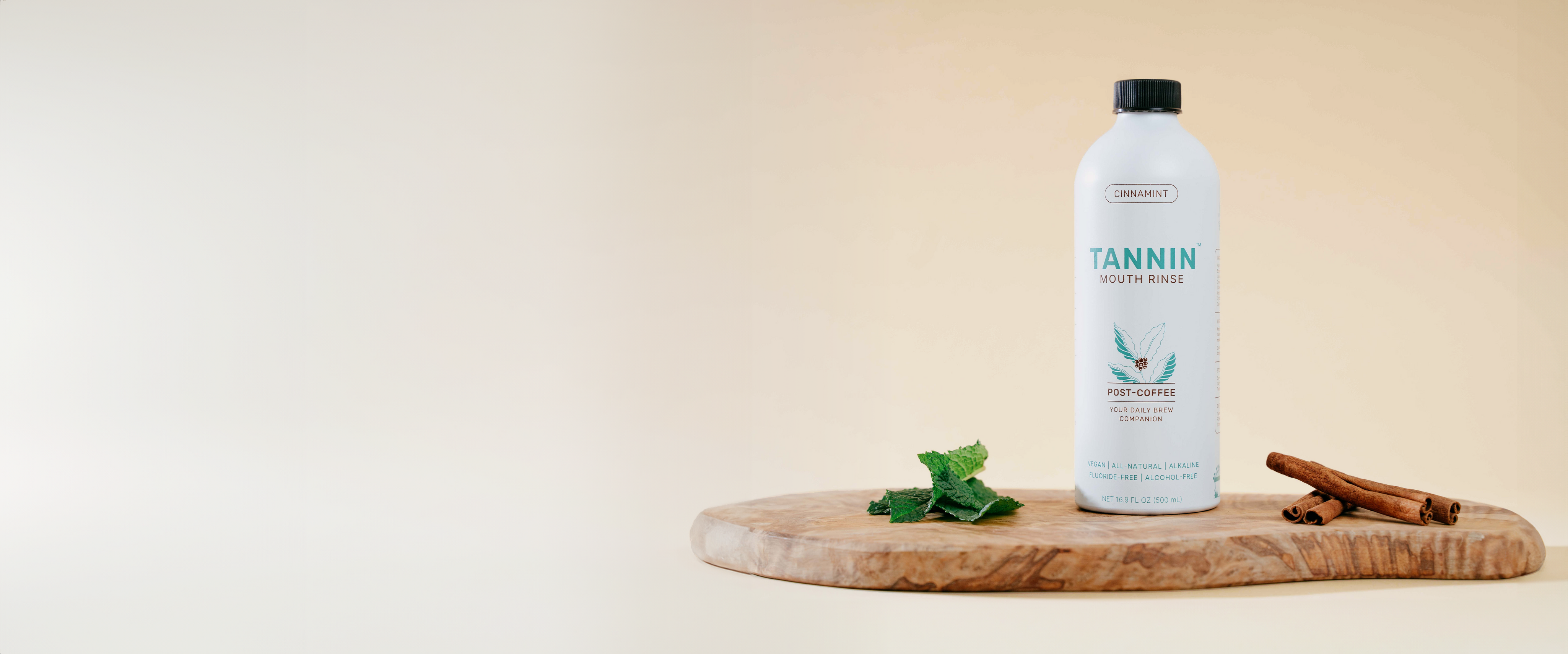 Tannin Post-Coffee Mouth Rinse bottle on a wooden board with mint leaves and cinnamon sticks, promoting a natural, fluoride-free oral care solution for fresh breath and healthier teeth, set against a minimalist neutral background.